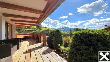 Geräumige Holzterrasse mit bequemen Sitzgelegenheiten und einem atemberaubenden Blick auf die umliegende Berglandschaft.