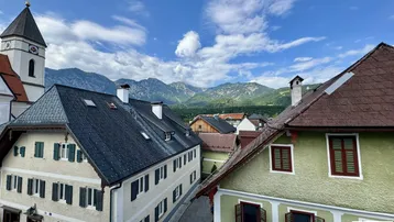 Panoramablick über ein malerisches Dorf mit Kirche und majestätischer Bergkulisse.
