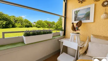 Heller Balkon mit Markise, Sitzgelegenheit und weitem Blick ins Grüne.