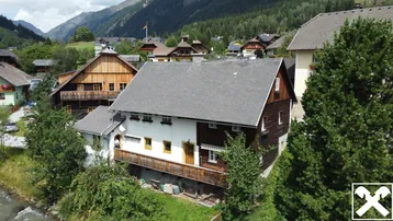 Ländliches Haus in den Bergen mit traditioneller Holzfassade und Balkon.