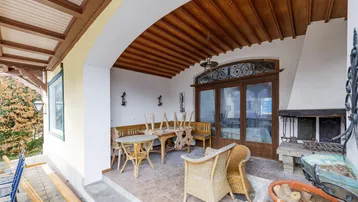 Überdachte Loggia mit rustikalen Holzmöbeln und einem gemauerten Grillbereich für gesellige Stunden.