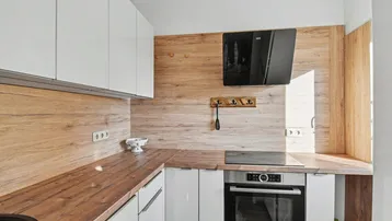 Moderne Küche mit weißen Hochglanzschränken, Holzoptik-Arbeitsplatten und integrierten Geräten.