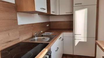 Moderne Einbauküche mit hellen Fronten, Holzoptik-Arbeitsplatten und integriertem Kochfeld.