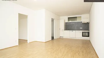 Heller offener Wohnbereich mit integrierter Küchenzeile und Parkettboden, ideal für modernes Wohnen.