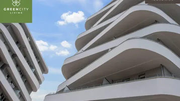 Moderne Architektur mit geschwungenen Balkonen und hellem Himmel, Teil einer Wohnanlage.