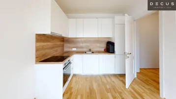 Helle, moderne Einbauküche mit weißen Schränken, Holzrückwand und Parkettboden.