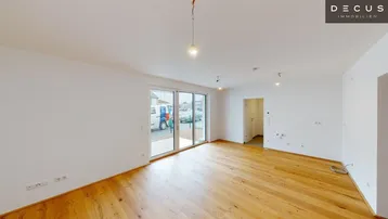 Helles Zimmer mit Holzboden und großen Schiebetüren, die viel Tageslicht hereinlassen.