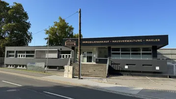 Modernes Geschäftsgebäude mit dunkler Fassade und großen Fenstern, gelegen an einer Straße.