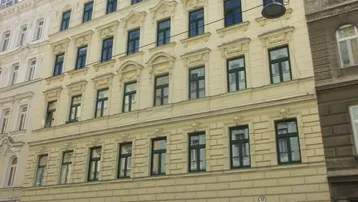 Klassische Fassade eines gepflegten Mehrfamilienhauses mit vielen Fenstern in städtischer Umgebung.