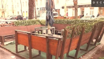Gemütlicher Außenbereich mit Holzbänken und Sonnenschirm, ideal für Gäste und Passanten.