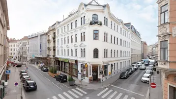 Historisches Eckgebäude in der Stadt mit klassischer Architektur und kleinen Balkonen.