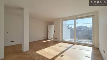 Helles, leeres Wohnzimmer mit Fischgrätparkett, großen Fenstern und Zugang zu einem Außenbereich.