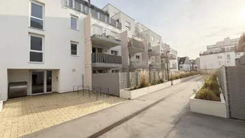 Moderne Wohnanlage mit Balkonen, Fahrradabstellplätzen und gepflastertem Zugangsbereich.