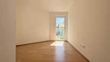 Sonniger Raum mit Parkettboden und direktem Zugang zu einem französischen Balkon.