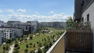 Blick vom Balkon auf eine weitläufige Grünfläche mit modernen Wohngebäuden im Hintergrund.