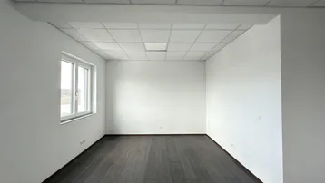 Heller Büroraum mit dunklem Laminatboden und abgehängter Decke, bereit für die individuelle Gestaltung.