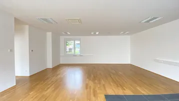 Geräumiger, leerer Büroraum mit hellem Holzboden und großen Fenstern, bereit zur individuellen Gestaltung.