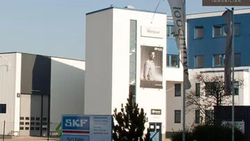 Außenansicht eines modernen Gewerbegebiets mit verschiedenen Büro- und Lagergebäuden unter blauem Himmel.
