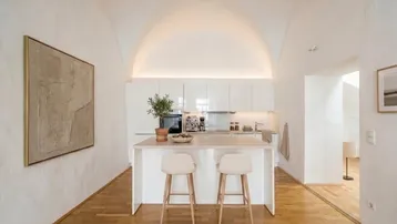 Moderne Küche mit Kücheninsel, weißen Hochglanzfronten und beeindruckender Gewölbedecke.