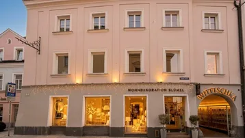 Historisches Gebäude mit beleuchteter Ladenfront und Wohnungen in der oberen Etage.