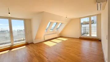 Helles Wohnzimmer mit Holzboden, Dachschrägen und Zugang zu zwei Terrassen.