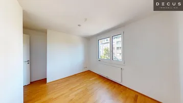 Helles, unmöbliertes Zimmer mit Holzparkettboden und großen Fenstern, ideal als Schlafzimmer.
