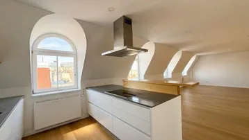 Moderne Küche mit Kochinsel, Dachschrägen und Rundbogenfenster in einem offenen Wohnbereich.