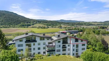 Luftaufnahme eines modernen Wohnkomplexes mit mehreren Balkonen und grüner Umgebung.