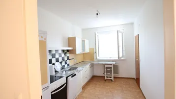 Funktionale Küche mit Fenster und Linoleumboden, ausgestattet mit grundlegenden Geräten und Stauraum.