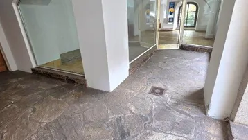 Geräumiger Eingangsbereich mit Natursteinboden, gewölbten Decken und Glaswänden, die den Blick nach draußen freigeben.