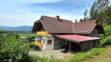Charmantes Einfamilienhaus mit Satteldach, Carport und weitem Blick auf die umliegende Landschaft.