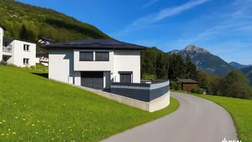 Modernes Einfamilienhaus mit weißer Fassade, Solaranlage und Bergblick in grüner Umgebung.