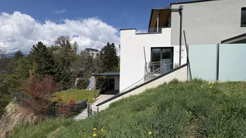 Seitenansicht des Hauses auf einem Hanggrundstück mit weitem Blick in die Natur.