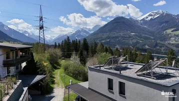 Dach des Hauses mit Photovoltaikanlage und weitem Blick auf die Bergkette.