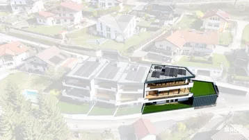 Luftaufnahme eines modernen Wohnkomplexes mit Solaranlagen auf dem Dach und umliegender Bebauung.