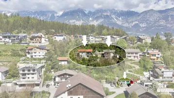 Luftaufnahme des Anwesens mit umliegenden Häusern und beeindruckendem Bergpanorama im Hintergrund.