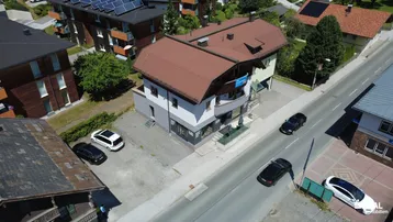 Luftaufnahme des Gebäudes von oben, mit Straße und Parkplätzen in der Umgebung.