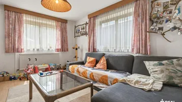 Gemütliches Wohnzimmer mit Sofa, Couchtisch und Fenstern, ideal für Familien.