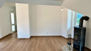 Gemütlicher Wohnbereich mit Holzboden und einem modernen Holzofen für zusätzliche Wärme.