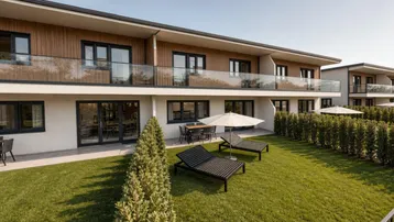 Moderne Wohnanlage mit Terrassen, Balkonen und gepflegtem Gartenbereich mit Liegestühlen.