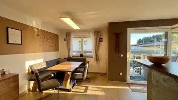 Gemütlicher Essbereich mit Holztisch und Eckbank, direktem Zugang zur Terrasse und viel Tageslicht.