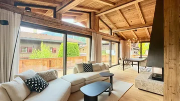 Helles, offenes Wohn- und Esszimmer mit Holzbalkendecke, Kamin und Zugang zur Terrasse.