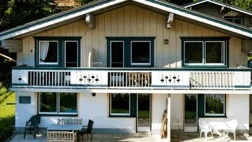 Charmantes Chalet mit Balkon und Terrasse, umgeben von grüner Natur und Bäumen.