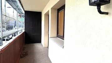 Langer Balkon mit einfacher Brüstung und Blick auf die Straße mit Gerüst.