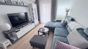 Helles Wohnzimmer mit modernem Sofa, TV-Möbel und Klimaanlage, ideal zum Entspannen.