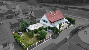 Luftaufnahme des Einfamilienhauses mit großem Garten, Terrasse und umliegender Nachbarschaft.