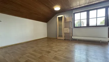 Geräumiges Dachzimmer mit Holzdecke, Laminatboden und Fenster mit Blick ins Grüne.
