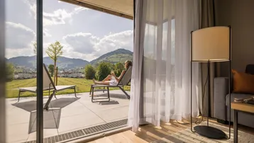 Sonniger Terrassenbereich mit Liegestühlen und weitem Blick auf die grüne Hügellandschaft.