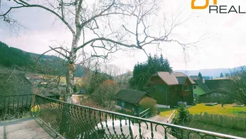 Balkon mit schmiedeeisernem Geländer und weitem Blick auf die grüne Landschaft und Berge.