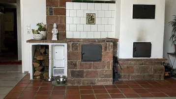 Detailansicht eines traditionellen Kachelofens mit Ziegeln und weißer Fliesenverkleidung im Wohnbereich.